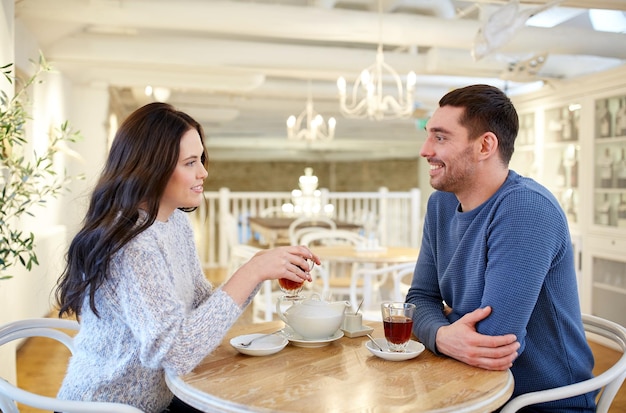 people, communication and dating concept - happy couple drinking tea at cafe or restaurant