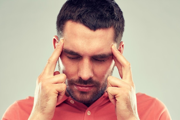 people, crisis, emotions and stress concept - man suffering from head ache or thinking over gray background