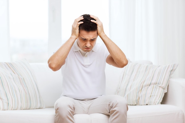 people, crisis, emotions and stress concept - unhappy man suffering from head ache at home