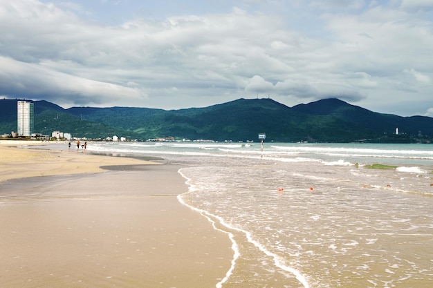 People at the distance at the China Beach in Danang in Vietnam. It is also called Non Nuoc Beach. South China Sea and Marble Mountains on the background.