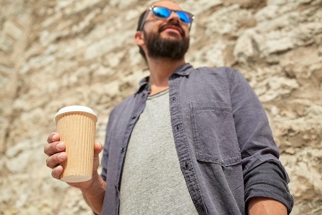 people, drinks, leisure and lifestyle concept - close up of man drinking coffee from disposable paper cup on city street