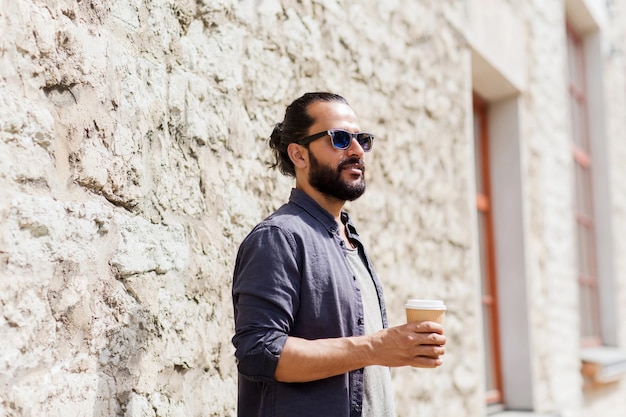 people, drinks, leisure and lifestyle - man drinking coffee from disposable paper cup on city street