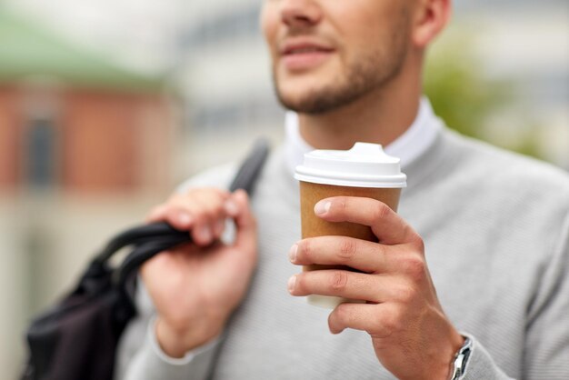 people, drinks and lifestyle - close up of man drinking coffee from disposable paper cup on city street