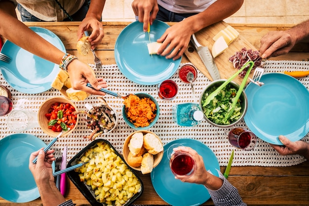 People eating together in friendship or family celebration with table full of food viewed from vertical top 