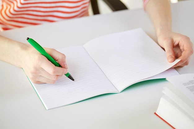 people and education concept - close up of female hands writing to notebook at school