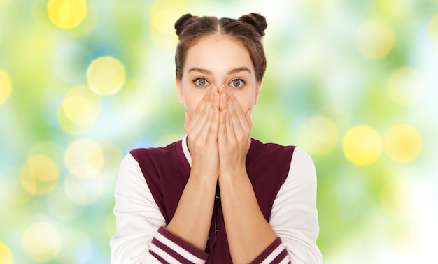 people, emotion, expression and teens concept - scared or confused teenage girl over green summer holidays lights background