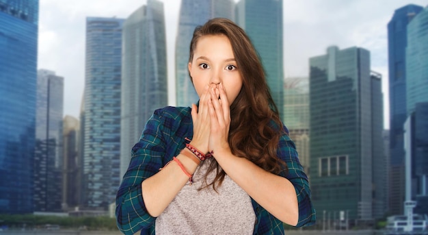 people, emotion, travel and tourism concept - scared teenage girl over singapore city background