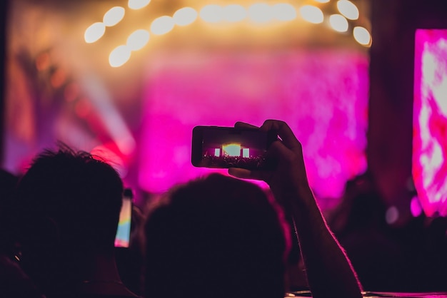 People enjoying rock concert and taking photos with cell phone at music festival