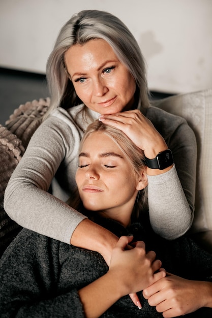 People and family concept happy smiling girl with mother hugging on sofa at home