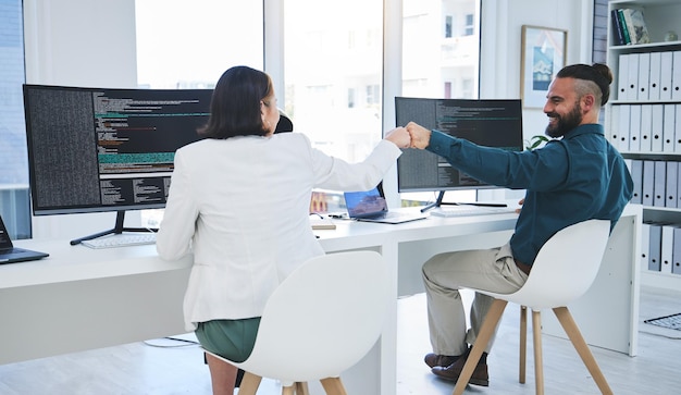 People fist bump and coding computer screen and software development or programming success in IT Developer or programmer support motivation or collaboration with coding or information technology