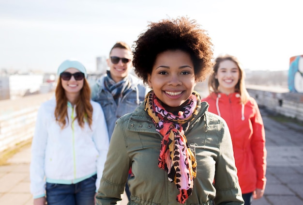 people, friendship and international concept - happy african american young woman or teenage girl in front of her friends on city street