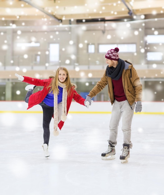 people, friendship, sport and leisure concept - happy couple holding hands on skating rink