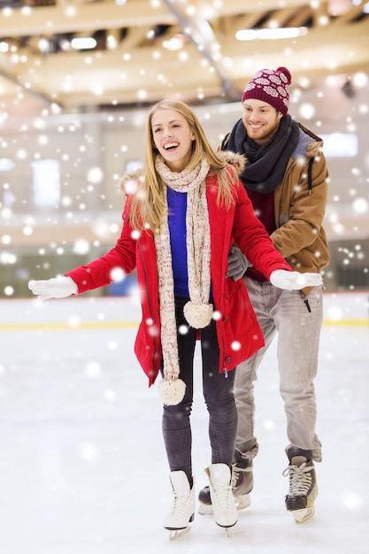 people, friendship, sport and leisure concept - happy couple on skating rink