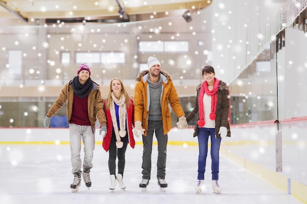 people, friendship, sport and leisure concept - happy friends on skating rink