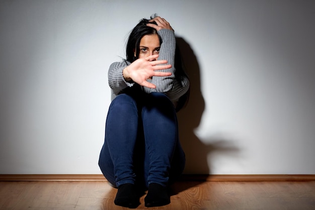 Photo people, grief and domestic violence concept - unhappy woman sitting on floor and crying at home