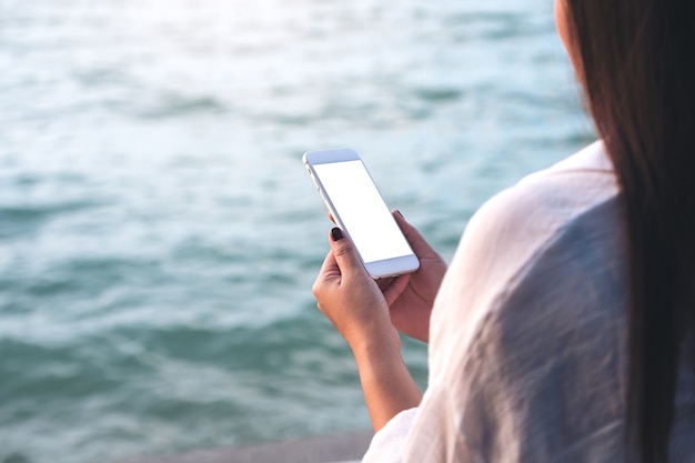 People hand using mockup smart phone by the sea