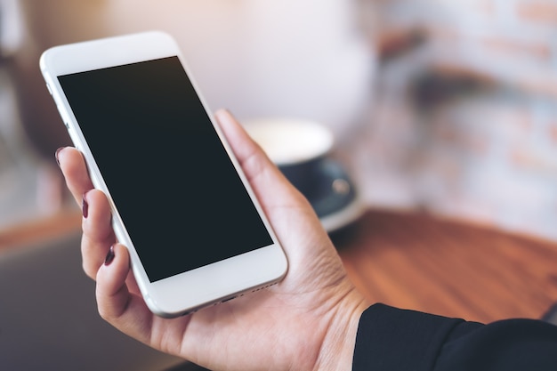 People hand using mockup smart phone in cafe