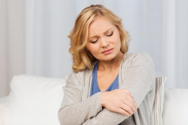 Photo people, healthcare and problem concept - unhappy woman suffering from pain in hand at home