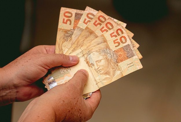 a people holding a brazilian banknotes of brazilian real