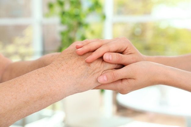 People holding hands together on blurred background closeup Help and elderly care concept