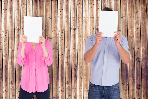 People holding sheets over faces against wooden planks