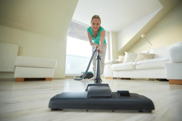 people, housework and housekeeping concept - happy woman with vacuum cleaner at home