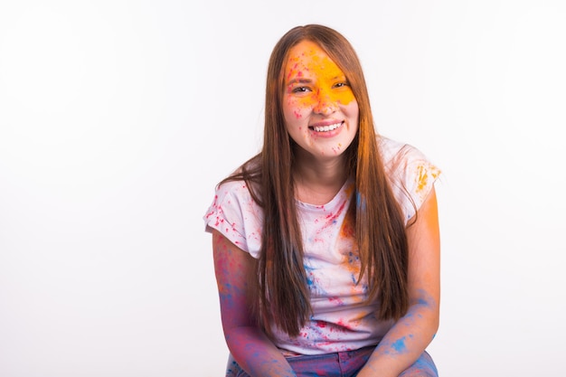 People and Indian holidays concept - Brunette woman covered with holi paint over white surface