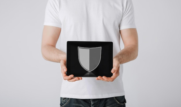 people, internet security and cyber protection concept - close up of man with virtual antivirus program shield icon on tablet pc computer screen over gray background