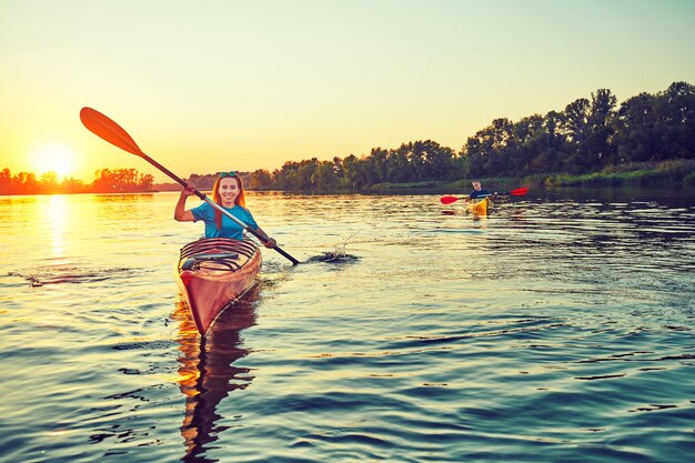 People kayak during sunset in the background. Have fun in your free time.