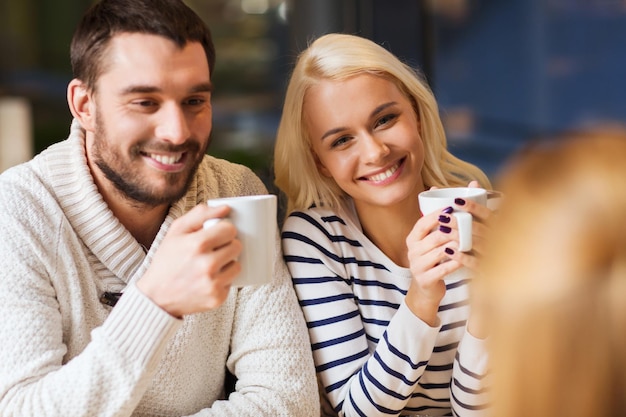 people, leisure and communication concept - happy friends meeting and drinking tea or coffee at cafe