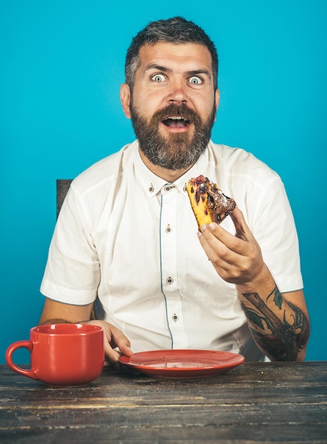 People leisure food concept handsome smiling man in white shirt sitting at desk eating breakfast