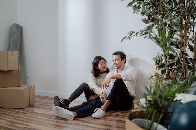 People in love are sitting leaning against wall in newly purchased apartment