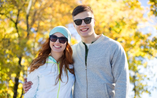 people, love, season and friendship concept - happy teenage couple walking over autumn park background