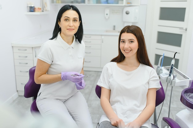 People medicine stomatology and health care concept happy female dentist with patient girl talking at dental clinic office