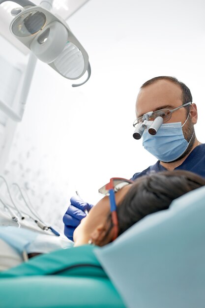 People, medicine, stomatology and health care concept - happy male dentist with woman patient at dental clinic office.