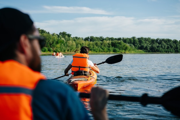 People in orange life jackets kayaking on a big wide river