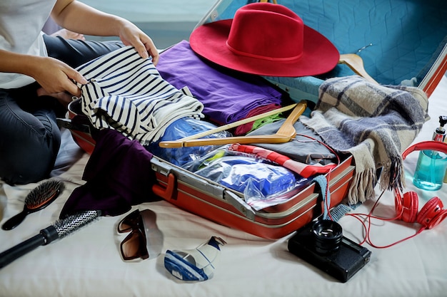 People packed suitcase with travel accessories on bed. Vacation concept 