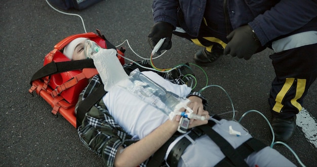 Photo people paramedic and emergency with patient in road on scene for help rescue and support emt team healthcare and oxygen mask for injured person on accident for medical service care and first aid