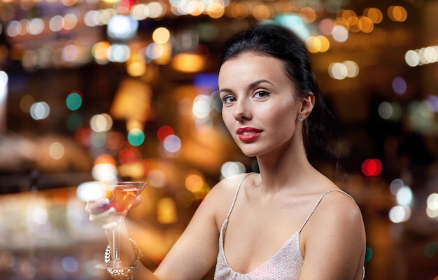 people, party, nightlife, drink and holidays concept - glamorous woman with cocktail at night club or bar