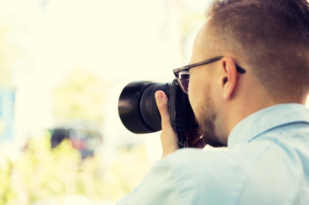 people, photography, technology, leisure and lifestyle - close up of male photographer with digital camera on city street