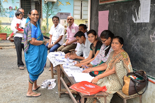 People and polling officers looks for a voters name in the list and complete the process of voting during election