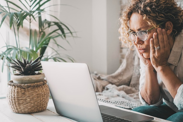 People and problems with computer concept Woman looking laptop display with worried expression on face Adult female read bad notification on notebook at home House leisure activity online Eyewear