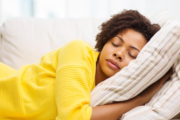 people, rest, comfort and leisure concept - african american young woman sleeping on sofa at home