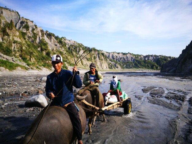 Photo people riding bullock cart against mountain