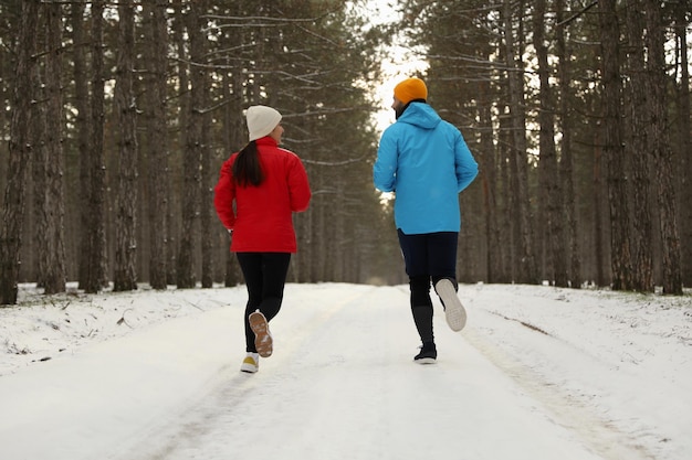 People running in winter forest back view Outdoors sports exercises