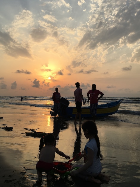 People on sea beach at sunset having fun