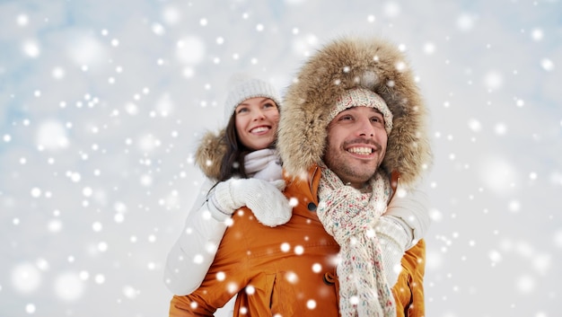 people, season, love and leisure concept - happy couple having fun over winter background