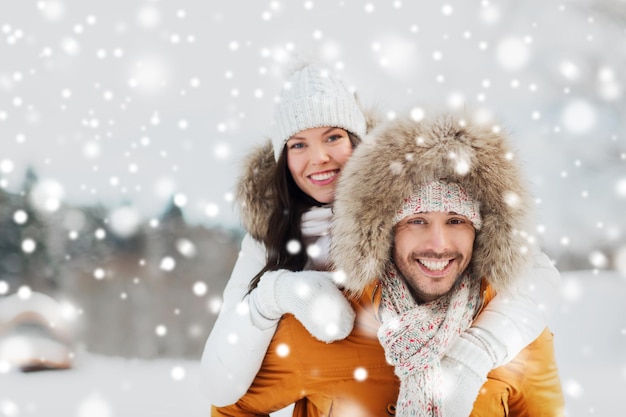 people, season, love and leisure concept - happy couple having fun over winter background