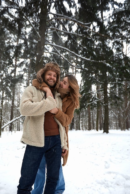 People season love and leisure concept happy couple hugging and laughing outdoors in winter Couple embracing and having fun in snowy winter park