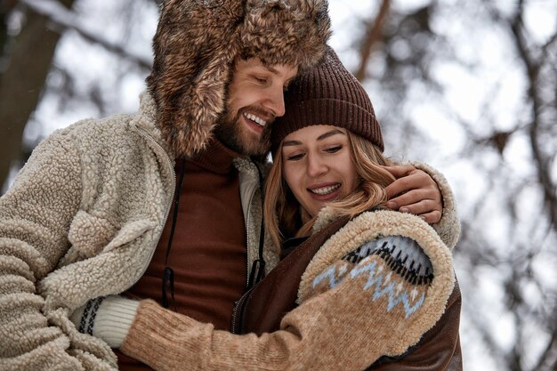 People season love and leisure concept happy couple hugging and laughing outdoors in winter Couple embracing and having fun in snowy winter park